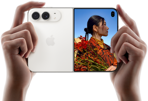 iPhone Duo, Star White colour, held by two hands in horizontal orientation, unfolded, left panel shows 48MP Dual Fusion rear cameras, right panel shows person getting their picture taken on outer display, the subject of the photo is able to see their face as their picture is getting taken using Duo Preview